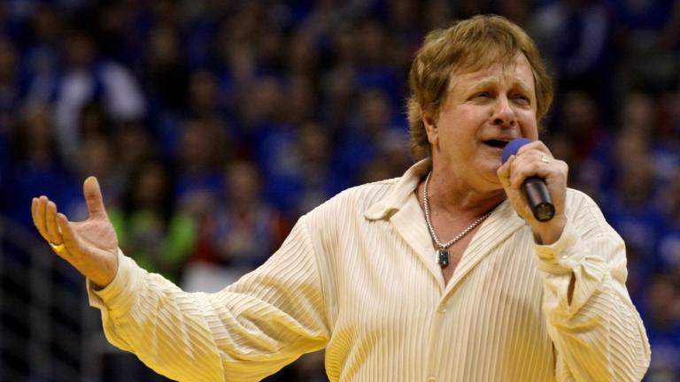 In this Jan. 25, 2010 file photo, Eddie Money sings the national anthem before an NCAA college basketball game between Kansas and Missouri in Lawrence, Kansas. Family members have said Eddie Money has died on Friday, Sept. 13, 2019. (AP Photo / Charlie Riedel, File)