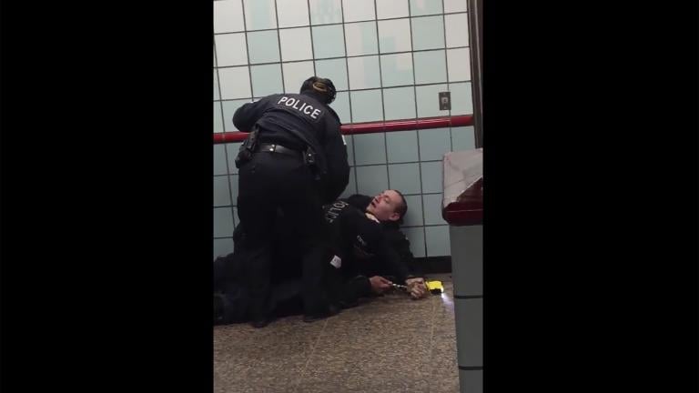 This Friday, Feb. 28, 2020 image from cellphone video shows Chicago police officers trying to apprehend a suspect inside a downtown Chicago train station. After a struggle with police, the suspect was shot as he fled up the escalator with the officers in pursuit. (Michael McDunnah via AP)