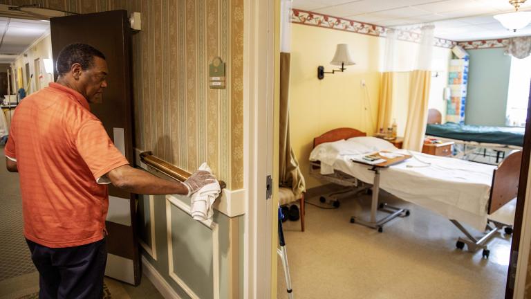 In this March 6, 2020, photo, Guilherme Gomes sanitizes a handrail at the South Shore Rehabilitation and Skilled Care Center, in Rockland, Mass. Staff at the 96-bed nursing home held an informational meeting for residents and have been stockpiling supplies, stepping up their daily disinfection routine and screening visitors for potential illness in recent days. (AP Photo / David Goldman)