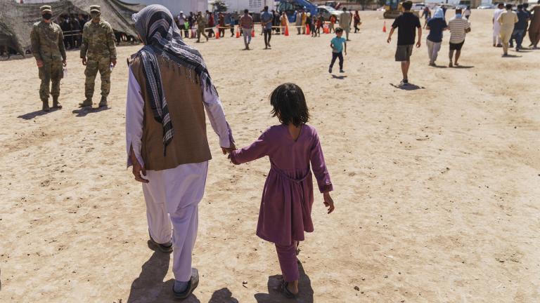 A man walks with a child through Fort Bliss' Doña Ana Village where Afghan refugees are being housed, in New Mexico, Friday, Sept. 10, 2021.