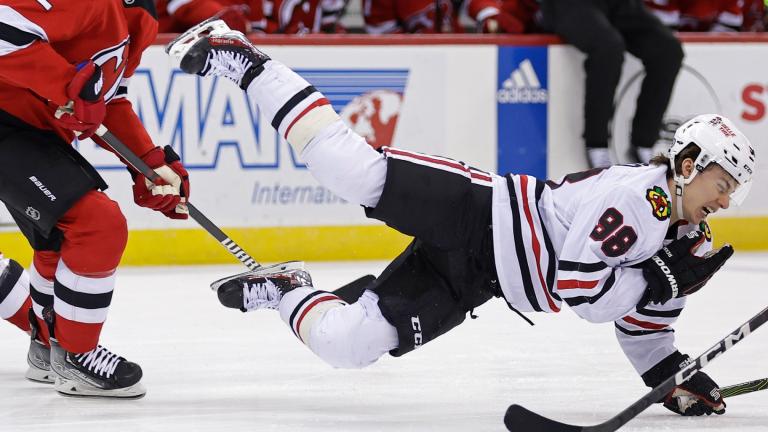Chicago Blackhawks center Connor Bedard falls to the ice after being checked by New Jersey Devils defenseman Brendan Smith (2) during the first period of an NHL hockey game Friday, Jan. 5, 2024, in Newark, N.J. (Adam Hunger / AP Photo)