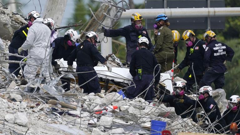 Rescue workers move a stretcher containing recovered remains at the site of the collapsed Champlain Towers South condo building, Monday, July 5, 2021 in Surfside, Fla. (AP Photo / Lynne Sladky)