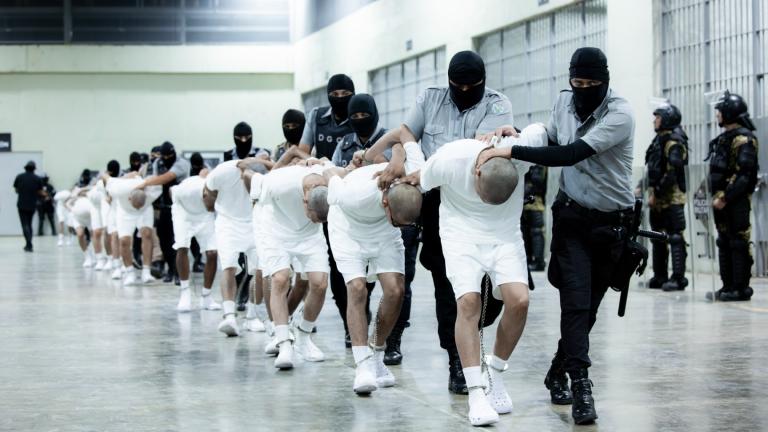 In this photo provided by El Salvador's presidential press office, prison guards transfer deportees from the U.S., alleged to be Venezuelan gang members, to the Terrorism Confinement Center in Tecoluca, El Salvador, Sunday, March 16, 2025. (El Salvador presidential press office via AP)