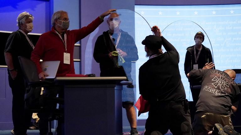 Members of the production crew inspect glass on stage which will serve as a barrier to protect the spread of COVID-19 as preparations take place for the vice presidential debate at the University of Utah, Tuesday, Oct. 6, 2020, in Salt Lake City. (AP Photo / Julio Cortez)