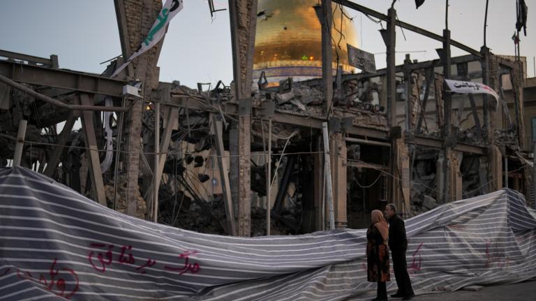 Pedestrians look at a destroyed building within the Grand Hosseiniyeh, with the mosque visible in the background, which officials at the site say was hit by U.S.-Israeli airstrikes Tuesday, in Zanjan, Iran, Saturday, April 4, 2026. (AP Photo / Francisco Seco)