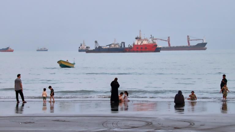 People spend time at a beach as commercial vessels are anchored in the Strait of Hormuz off Bandar Abbas, Iran, Wednesday, Aug. 5, 2026. (Amirhosein Khorgooi / ISNA via AP)