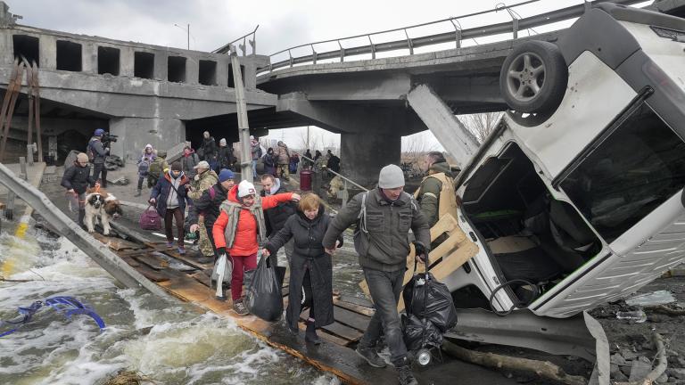 People cross an improvised path under a destroyed bridge while fleeing the town of Irpin close to Kyiv, Ukraine, Monday, March 7, 2022. (AP Photo / Efrem Lukatsky)