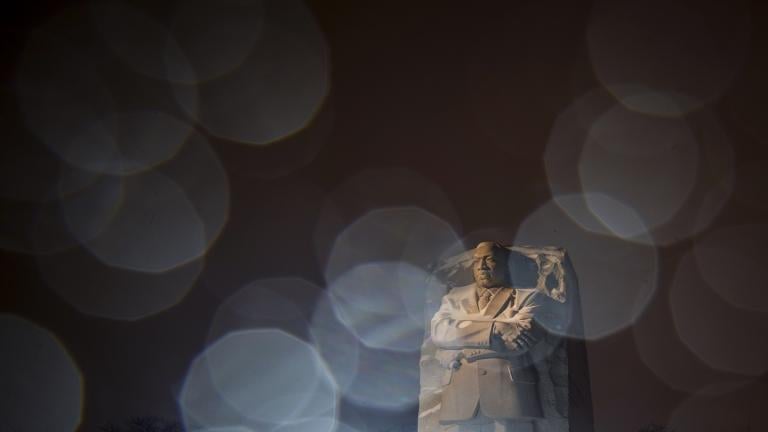 In a long exposure photo, lights from a snowplow illuminate sleet at the Martin Luther King Jr. Memorial in Washington, Sunday, Jan. 16, 2022. Ceremonies scheduled for the site on Monday, to mark the Martin Luther King Jr. national holiday, have been canceled because of the weather. (AP Photo/Carolyn Kaster)