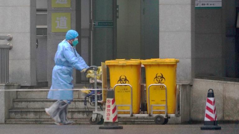 In this Wednesday, Jan. 22, 2020, file photo, a staff member moves bio-waste containers past the entrance of the Wuhan Medical Treatment Center in Wuhan, China, where some people infected with a new virus are being treated. (AP Photo / Dake Kang, File) In this Wednesday, Jan. 22, 2020, file photo, a staff member moves bio-waste containers past the entrance of the Wuhan Medical Treatment Center in Wuhan, China, where some people infected with a new virus are being treated. (AP Photo / Dake Kang, File)