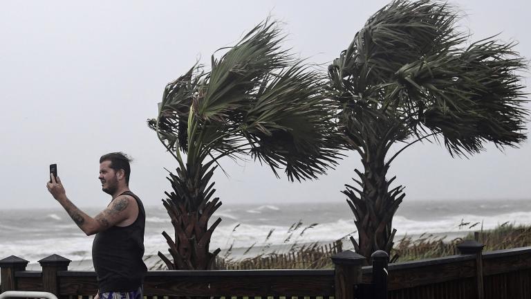 William Ellinge, of Murrells Inlet, S.C., takes photos of waves crashing on the shore in Myrtle Beach, S.C., Thursday, Sept. 5, 2019, as Hurricane Dorian moves north off the coast. (Ken Ruinard / The Independent-Mail via AP)