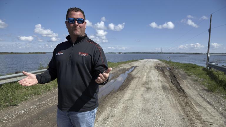 In this May 10, 2019 photo, Brett Adams gestures as he stands where the road to his flooded farm disappears under flood waters, with the farm buildings seen in the background, in Peru, Neb. (AP Photo / Nati Harnik)