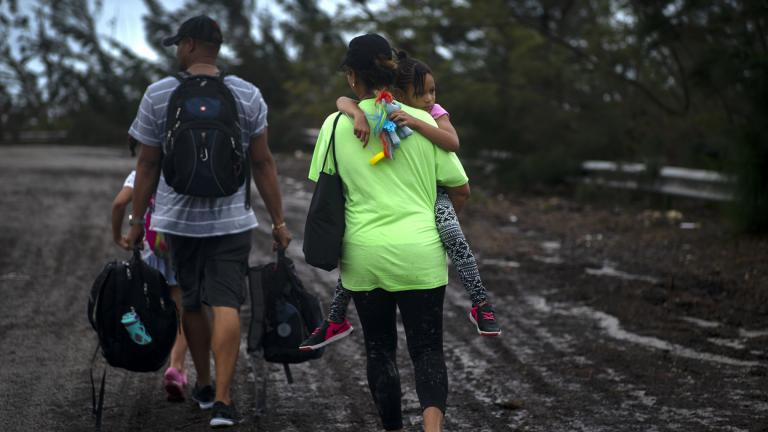 A family walks on a road after being rescued from the floodwaters of Hurricane Dorian, near Freeport, Grand Bahama, Bahamas on Tuesday Sept. 3, 2019. They were rescued by volunteers who drove a bus into the floodwaters to pick them up. (AP Photo / Ramon Espinosa)