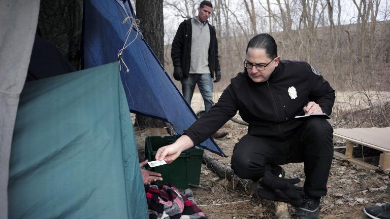 In this Tuesday, Feb. 12, 2019 file photo, Worcester Police Officer Angel Rivera, right, returns a license to an unidentified man as Rivera asks if he has been tested for Hepatitis A at the entrance to a tent where the man spent the night in a wooded area, in Worcester, Mass. (AP Photo / Steven Senne) In this Tuesday, Feb. 12, 2019 file photo, Worcester Police Officer Angel Rivera, right, returns a license to an unidentified man as Rivera asks if he has been tested for Hepatitis A at the entrance to a tent where the man spent the night in a wooded area, in Worcester, Mass. (AP Photo / Steven Senne)