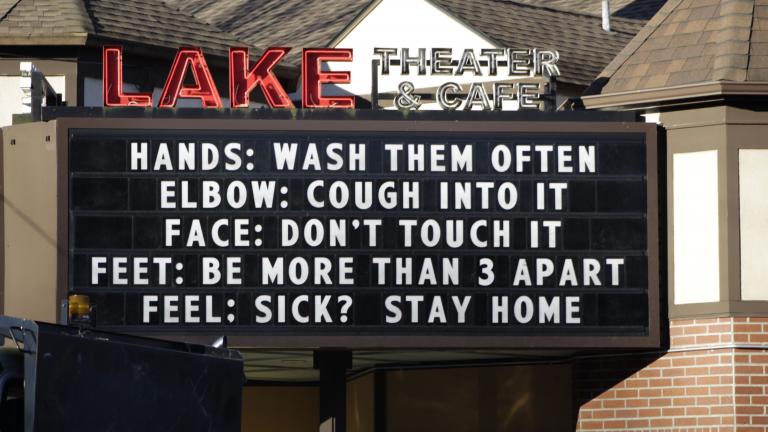 In this March 17, 2020 file photo, a marquee outside the Lake Theater & Café in downtown Lake Oswego, Oregon, reminds people to practice social distancing and stay home if sick. (AP Photo / Gillian Flaccus, File)