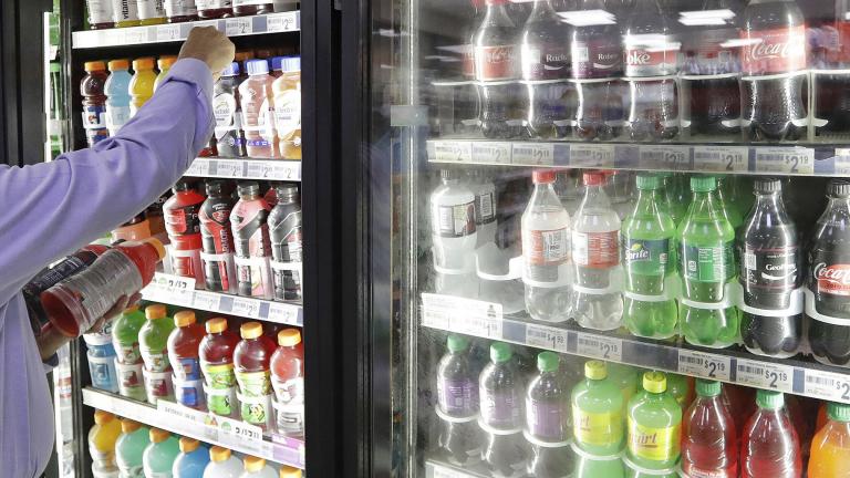 In this Monday, Oct. 1, 2018 file photo, a shop owner reaches into a drink display refrigerator at his convenience store in Kent, Wash. (AP Photo / Elaine Thompson)