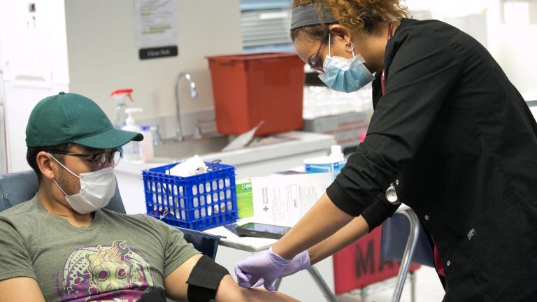 A Red Cross blood donor rolls up a sleeve to give blood during the COVID-19 outbreak at the Rockville Donation Center in Maryland. (Photo by Dennis Drenner / American Red Cross)
