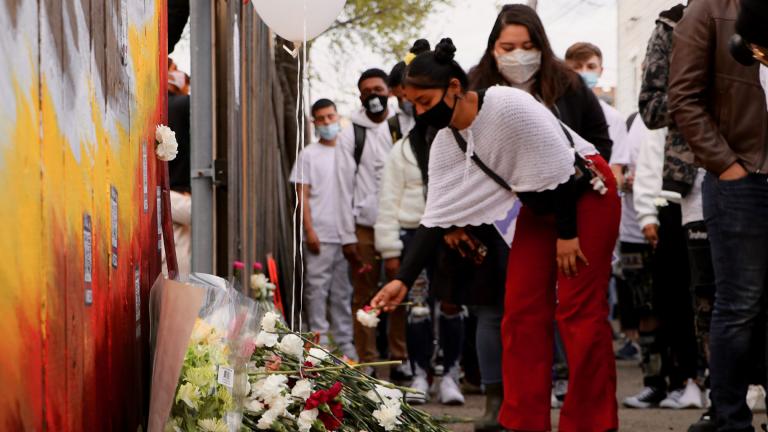 A person lays a flower at a memorial for 13-year-old Adam Toledo in Chicago’s Little Village neighborhood during a peace walk on April 18, 2021. (Evan Garcia / WTTW News)