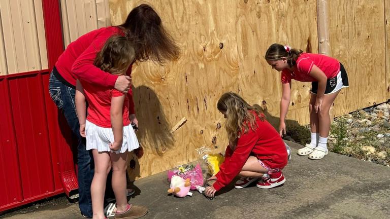 Jennifer Walston, 43, hugs daughter Lexi Walston, 6, while sisters Briley Walston, 9 and Madison Foster, 10, place flowers and stuffed animals at the site where several were killed Monday, when a car barreled through a building used for an after-school camp in Chatham, Ill., on Tuesday, April 29, 2025. (AP Photo / John O'Connor)