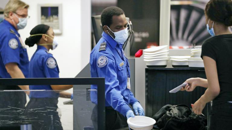 TSA officers wear protective masks at a security screening area at Seattle-Tacoma International Airport Monday, May 18, 2020, in SeaTac, Wash. (AP Photo/Elaine Thompson)