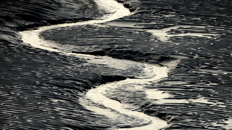 A channel flows through the mud flats along the Seward Highway and Turnagain Arm in Alaska in this Oct. 25, 2014, file photo. (Bob Hallinen / Anchorage Daily News via AP)