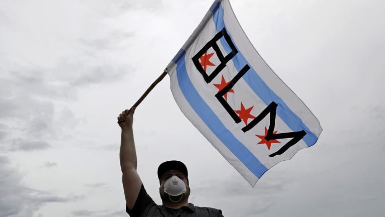 In this June 3, 2020, file photo, a protester waves a city of Chicago flag emblazoned with the acronym BLM for Black Lives Matter, outside the Batavia, Ill., City Hall during a protest over the death of George Floyd. (AP Photo / Nam Y. Huh, File) In this June 3, 2020, file photo, a protester waves a city of Chicago flag emblazoned with the acronym BLM for Black Lives Matter, outside the Batavia, Ill., City Hall during a protest over the death of George Floyd. (AP Photo / Nam Y. Huh, File)