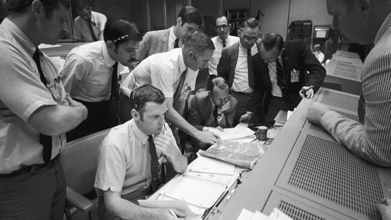 In this April 15, 1970 photo made available by NASA, a group of flight controllers gather around the console of Glenn S. Lunney, foreground seated, Shift 4 flight director, in the Mission Operations Control Room of Mission Control Center in Houston. (NASA via AP) 