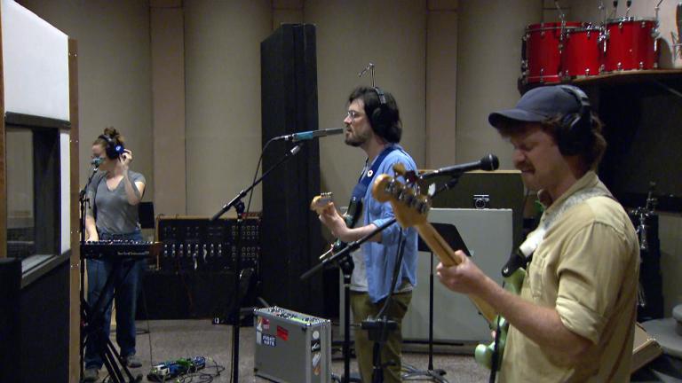 Three members of Chicago Band Así Así rehearses in a practice space. (WTTW News)