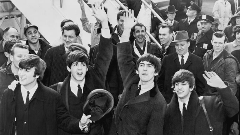 The Beatles wave to fans after arriving at Kennedy Airport in February 1964. 