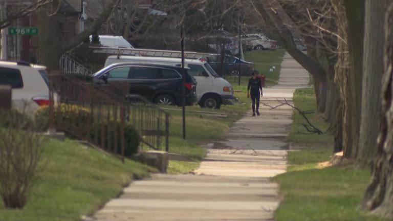 A lone figure walks along a residential street in the Beverly neighborhood of Chicago on March 30, 2020. (WTTW News)