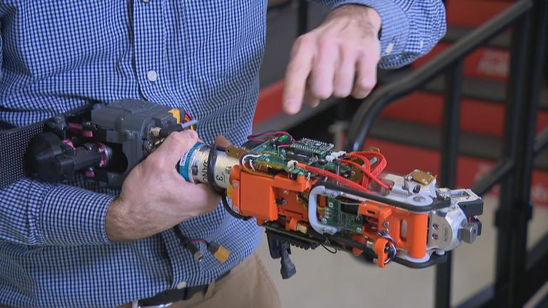 Frank Ursetta holds a portion of a bionic limb being developed by the Shirley Ryan AbilityLab in Chicago. (WTTW News)