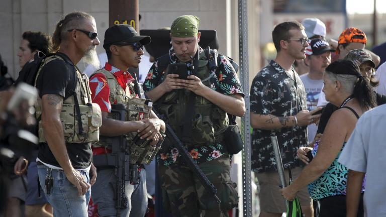 In this June 20, 2020 file photo, gun-carrying men wearing Hawaiian print shirts associated with the boogaloo movement watch a demonstration near where President Trump had a campaign rally in Tulsa, Okla. (AP Photo / Charlie Riedel, File)