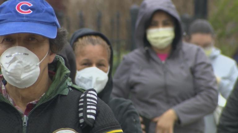 People wearing masks line up for a food drive in Brighton Park on Chicago’s Southwest Side on April 23, 2020. (WTTW News)