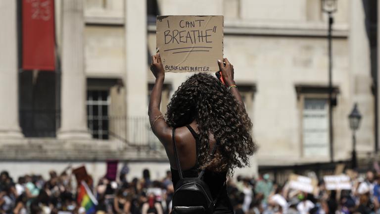 A woman holds up a banner as people gather in Trafalgar Square in central London on Sunday, May 31, 2020 to protest against the recent killing of George Floyd by police officers in Minneapolis that has led to protests across the U.S. (AP Photo / Matt Dunham)