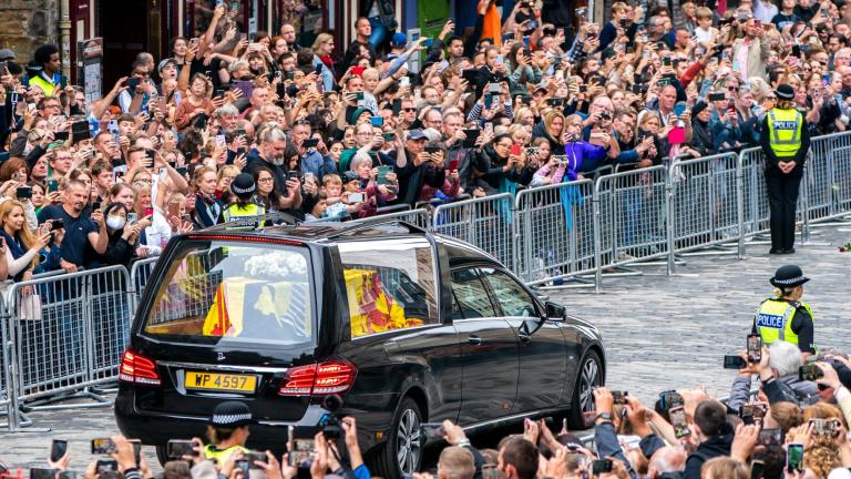 The hearse carrying the coffin of Queen Elizabeth II, draped with the Royal Standard of Scotland, passes the City Chambers on the Royal Mile, Edinburgh, Sunday, Sept. 11, 2022 on the journey from Balmoral to the Palace of Holyroodhouse in Edinburgh, where it will lie in rest for a day. (Jane Barlow / Pool Photo via AP)