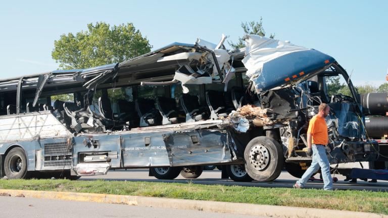 A worker helps clear the wreckage of a Greyhound bus that collided with tractor-trailers on the exit ramp to a rest area on westbound Interstate 70 in Highland, Ill., on Wednesday, July 12, 2023. (Christian Gooden / St. Louis Post-Dispatch via AP)