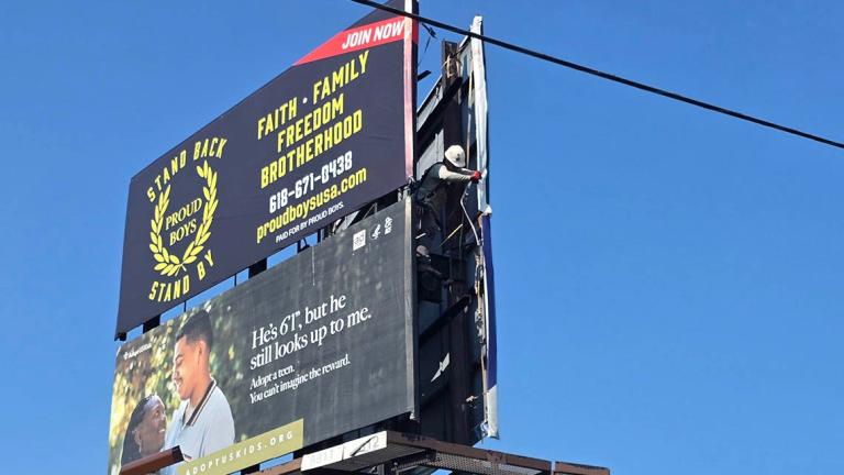 A Lamar Advertising representative on Monday moves an ad for the far-right extremist group Proud Boys; the sign was taken down entirely around noon Tuesday. (Molly Parker / Capitol News Illinois) 
