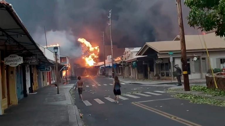 People watch as smoke and flames fill the air from raging wildfires on Front Street in downtown Lahaina, Maui on Tuesday, Aug. 8, 2023. (Alan Dickar via AP)