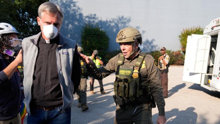 Greg Bovino, the chief patrol agent for the U.S. Border Patrol El Centro sector, right, walks along a protester with his hands behind his back near an Immigration and Customs Enforcement facility in Broadview, Ill., Friday, Oct. 3, 2025. (AP Photo/Erin Hooley).