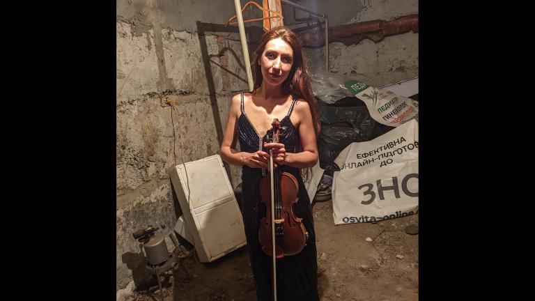 Vera Lytovchenko holds her violin as she poses for a photo in a basement of an apartment building in Kharkiv, Ukraine, Sunday March 6, 2022. (Vera Lytovchenko via AP)