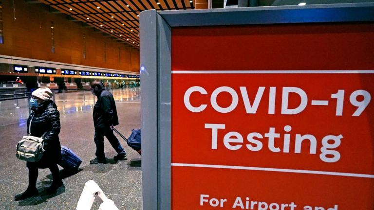 FILE - Travelers pass a sign near a COVID-19 testing site in Terminal E at Logan Airport, on Dec. 21, 2021, in Boston. (Charles Krupa / AP Photo, File)