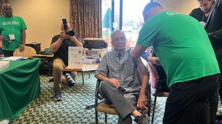 Rush Hospital outreach street nurse Joshua Dueshop vaccinates a resident of the Martha Washington senior apartments in North Center. (Amanda Vinicky / WTTW News)