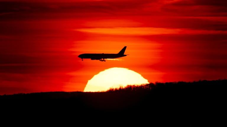 FILE - A passenger jet on approach to Newark Liberty International Airport flies over the setting sun in Newark, N.J., March 27, 2019. (AP Photo / J. David Ake, File)
