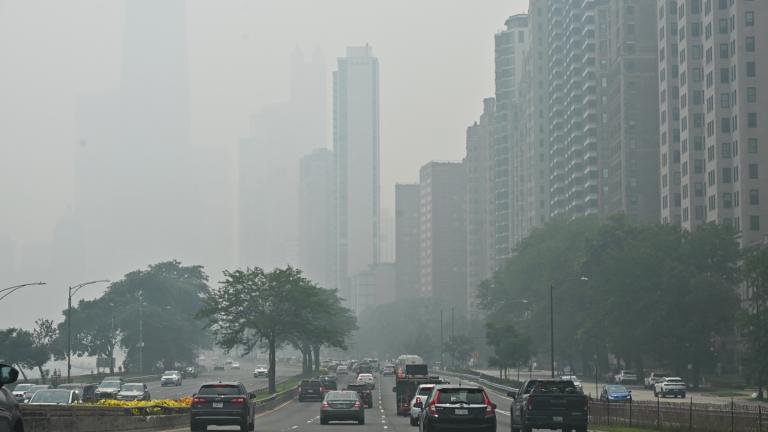 The iconic John Hancock Center is reduced to a faint silhouette behind a thick shroud of Canadian wildfire smoke as vehicles head southbound on DuSable Lake Shore Drive near the Gold Coast neighborhood on Thursday, July 16, 2026. (Victor Hilitski / WTTW News)