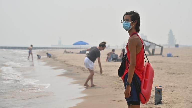 A lifeguard patrols the beach with a facemask shortly before the Chicago Park District closed the beaches for the day due to hazardous air quality on July 16, 2026. (Victor Hilitski / WTTW News)
