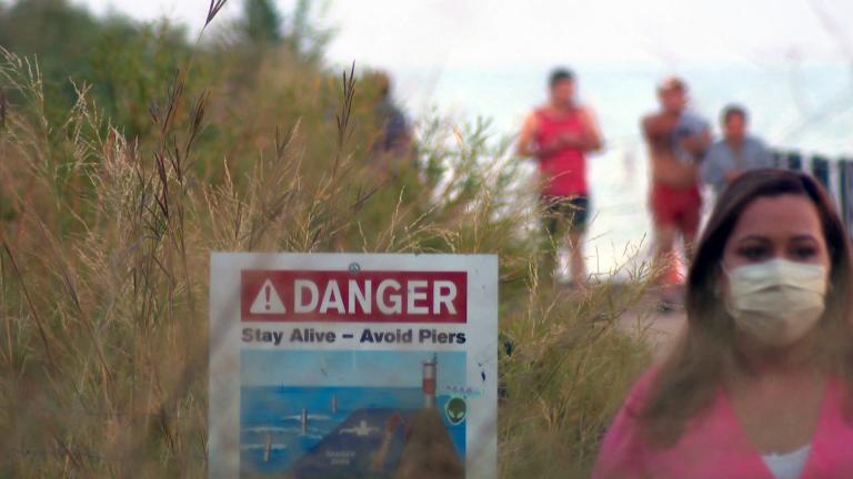 A sign on the Chicago lakefront warns people to avoid potentially dangerous areas, such as piers. (WTTW News)