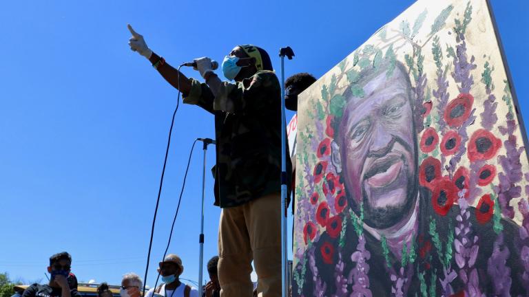 Standing before a painting of George Floyd, a speaker addresses the crowd in Seward Park on Saturday, June 6, 2020. (@EvanRGarcia / Twitter)