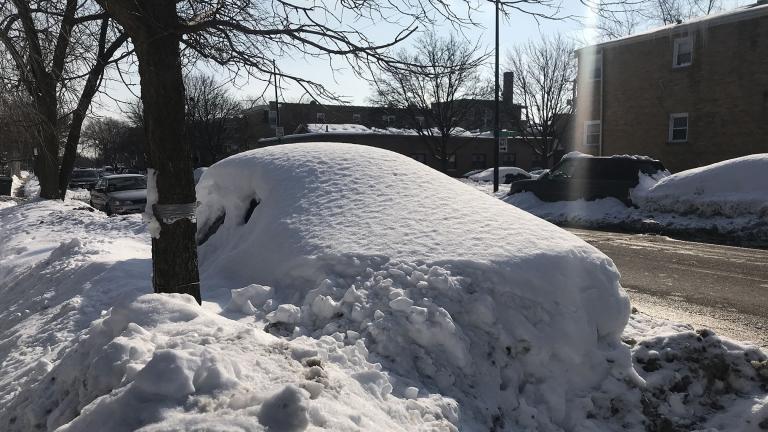 A car parked on a street in Chicago is buried by snow from recent storms. Sunshine and warmer temperatures on Saturday, Feb. 20, 2021 melted some snow, but there is still plenty to shovel. (WTTW News)
