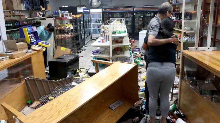 Yogi Dalal hugs his daughter Jigisha Monday, Aug. 10, 2020, after she arrived at the family food and liquor store and as his other daughter Kajal, left, bows her head after the family business was vandalized in downtown Chicago. (AP Photo / Charles Rex Arbogast) 