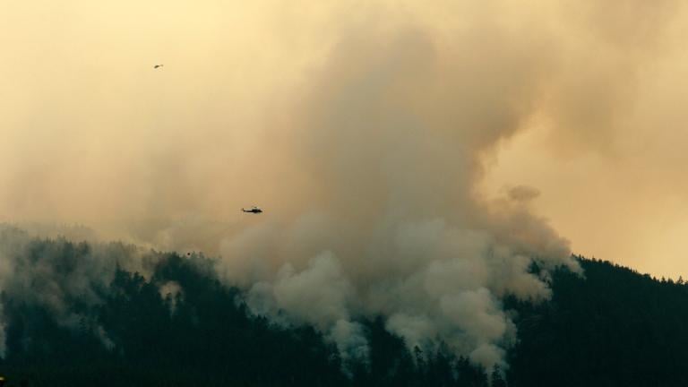A helicopter flies by the Wesley Ridge wildfire near Cameron Lake where an out-of-control fire continues to burn near Coombs, British Columbia, Aug. 3, 2025. (Chad Hipolito / The Canadian Press via AP)