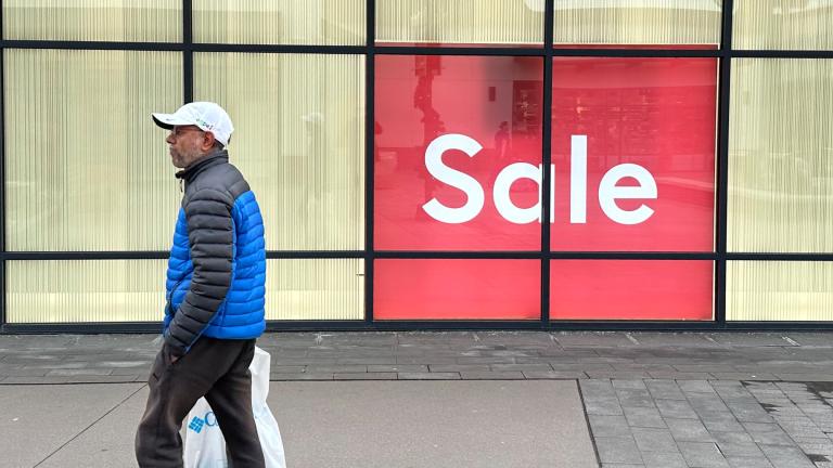 A shopper passes by a sign trumpeting a sale at a clothing store in the Thornton Premium Outlets Monday, Dec. 18, 2023, in Thornton, Colo. (AP Photo / David Zalubowski)